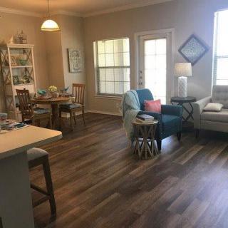 A cozy living room with wooden flooring, comfortable seating, and natural light.
