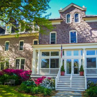 A beautiful historic stone building with a charming entrance and colorful garden.