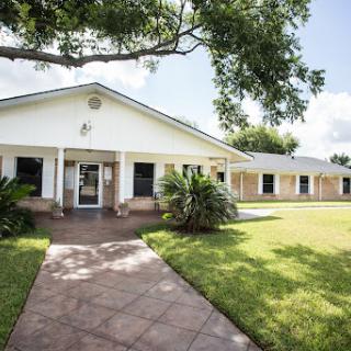 A charming single-story residential building with a welcoming entrance and lush green surroundings.