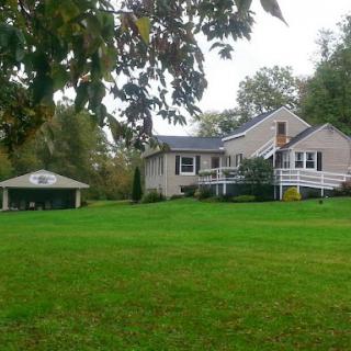 A serene suburban house surrounded by lush green grass and a nearby shed.