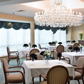 An elegant dining room setup with tables and chairs under a grand chandelier.
