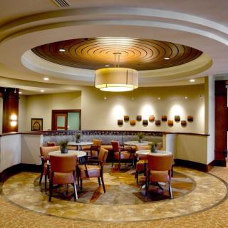 A modern lounge area featuring round tables and comfortable seating with elegant lighting and decor.