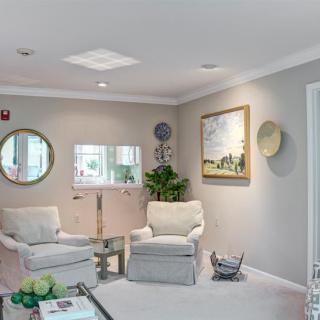 A cozy waiting room with comfortable chairs, decorative mirrors, and artwork on the walls.
