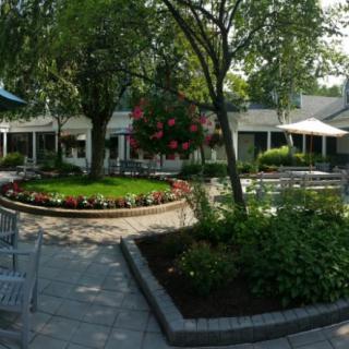 A tranquil outdoor garden with seating areas, surrounded by lush greenery and colorful flowers.