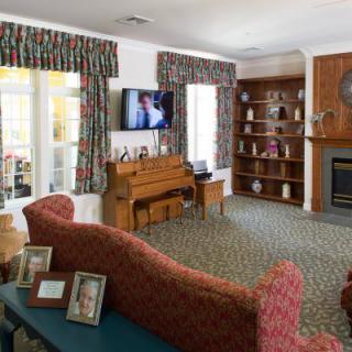 A cozy living room with a sofa, television, fireplace, and bookshelves.