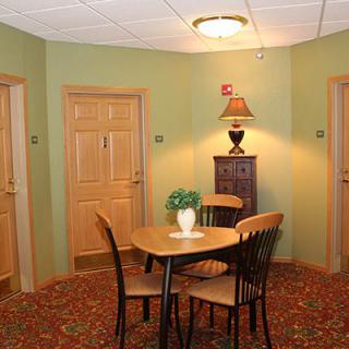 A cozy hallway corner with a wooden table and chairs, adorned with a lamp and decorative plant.