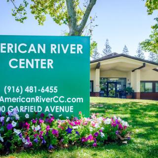 An outdoor view of the American River Center with a prominent sign and surrounding landscaping.