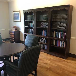 A cozy reading area featuring a wooden bookshelf filled with books, surrounded by a table and chairs.