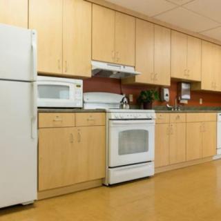 A modern kitchen with wooden cabinets, equipped with a refrigerator, stove, and microwave.
