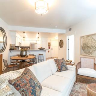 A modern living room with an open kitchen, featuring a white sofa and stylish decor.