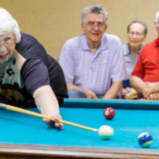 A group of seniors enjoying a game of billiards together.