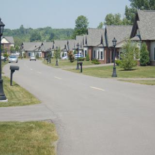 A quiet suburban street lined with houses and mailboxes under a clear sky.