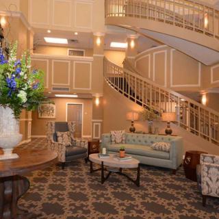 A luxurious lobby featuring elegant decor with a grand staircase, plush seating, and ornate lighting.