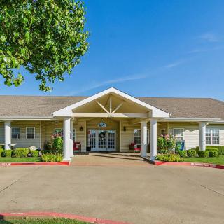 A sunny day view of a residential building with a well-maintained lawn and entrance.