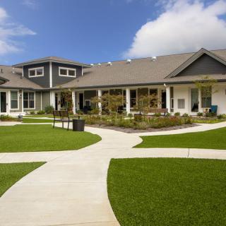 A modern house with a well-maintained lawn and multiple pathways under a clear blue sky.