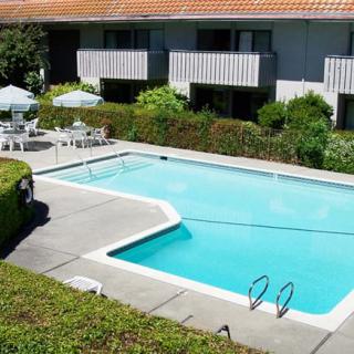 Outdoor swimming pool area at an apartment complex with patio furniture.