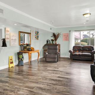 Spacious living room with hardwood floors, featuring a sofa, mirror, and decorative elements.