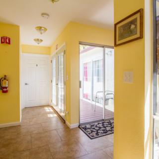 A bright hallway with yellow walls, featuring a tile floor and natural light streaming through the windows.