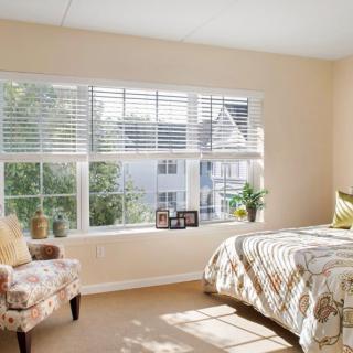 A cozy bedroom with a large window allowing natural sunlight to brighten the space.