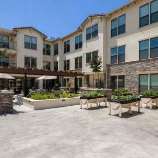 A modern residential building with a spacious outdoor courtyard under a clear blue sky.