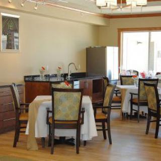A cozy dining area with neatly arranged tables and chairs, featuring tablecloths and a wooden floor.