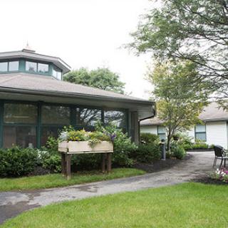 A serene view of a modern building surrounded by lush greenery and a well-maintained pathway.