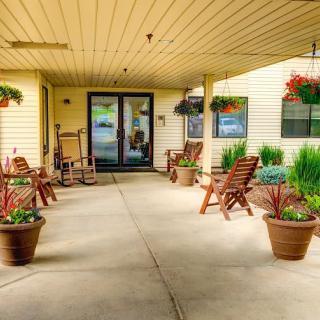 An inviting patio area with wooden chairs, potted plants, and hanging baskets.