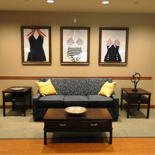 A cozy living room setup featuring a patterned sofa, two small side tables, and framed artwork on the wall.