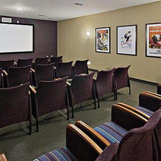 A cozy media room featuring comfortable seating, a projector screen, and movie posters on the walls, perfect for intimate screenings.