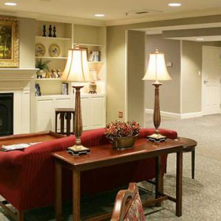 A cozy living room with elegant interior design, featuring a red sofa, lamps, and a fireplace.