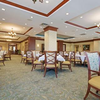 Spacious dining area with neatly arranged tables and chairs, featuring elegant interior design and warm lighting.