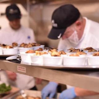 Chefs preparing and plating dishes in a busy kitchen.