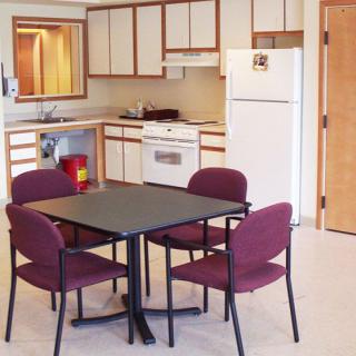 A modern kitchen with a dining table and chairs, featuring appliances like a fridge and oven.
