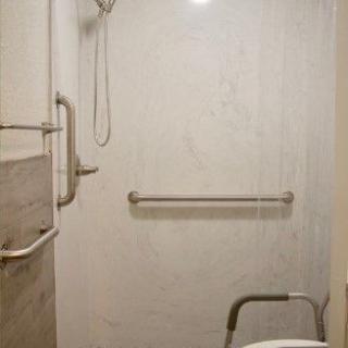 An accessible shower with grab bars and a shower chair.