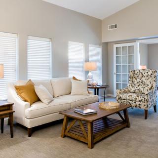 A cozy living room with modern decor featuring a white sofa, patterned armchair, wooden coffee table, and soft lighting.