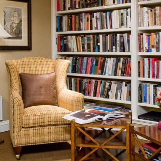 A cozy reading nook with an armchair and a bookshelf filled with books.