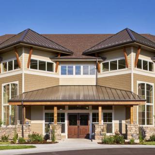 A modern, two-story residential building with wood accents and large windows.