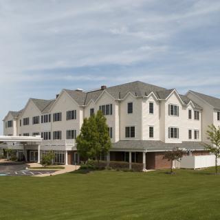 A large residential building with a well-maintained lawn and cloudy sky in the background.