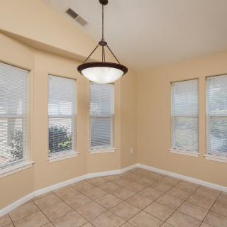 A bright, empty room with large windows and a central chandelier.