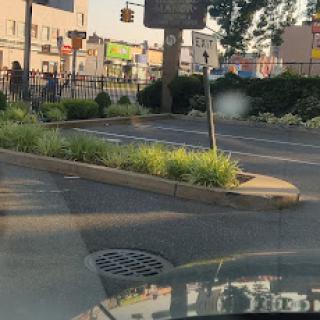 A view of a parking area with greenery and signage in an urban setting.