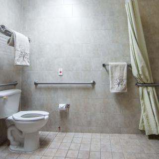 A clean and simple bathroom featuring a toilet, shower area, and neatly arranged towels.