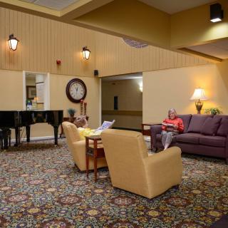 A cozy lobby with comfortable seating, a piano, and warm lighting.