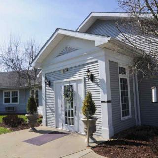 A view of the front entrance of a residential building with white siding and decorative planters.