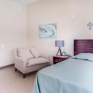 A cozy bedroom with a comfortable chair, stylish lamp, and neatly made bed.