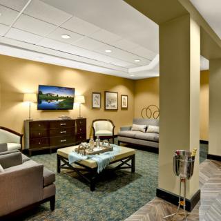 A cozy lobby seating area with comfortable furniture and a wall-mounted television.