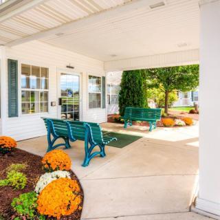 A welcoming entrance with green benches and colorful flowers.