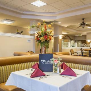 A well-decorated restaurant interior with a neatly set dining table, featuring a menu and a flower arrangement.