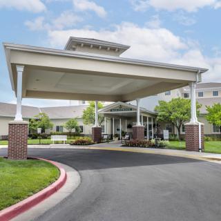 A large building entrance featuring a covered driveway and well-maintained landscaping.