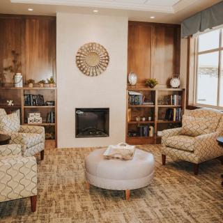 A cozy living room with a fireplace, armchairs, and warm wooden accents.