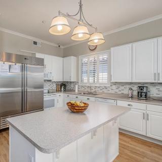A modern kitchen featuring white cabinets and a large island under stylish pendant lighting.